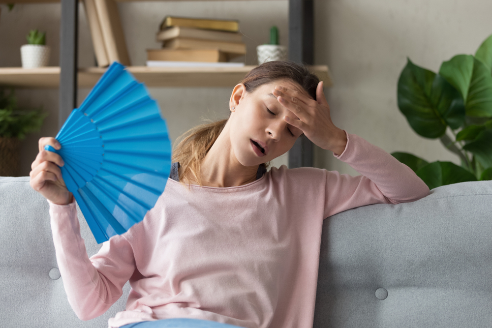 Overheated,Millennial,Woman,Sit,On,Couch,At,Home,Feel,Warm